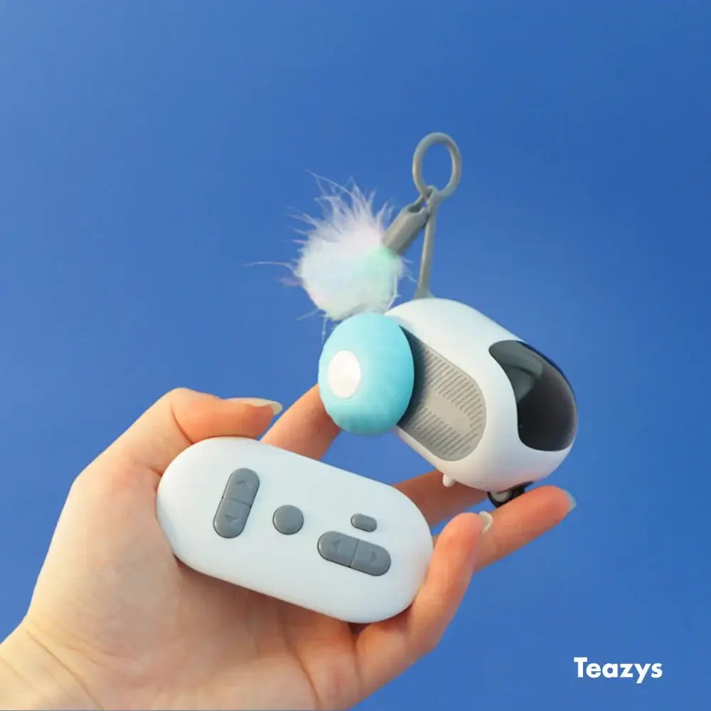 A hand holds a sleek white remote next to the TURBO TAIL 2.0, a stylish white-blue keychain with a fluffy pom-pom, against a vibrant blue background.